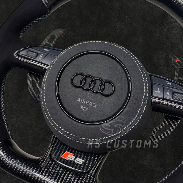 RS CUSTOMS Audi RS steering wheel with carbon fiber, Alcantara, and white stitching. Features a white racing stripe at 12 o'clock.