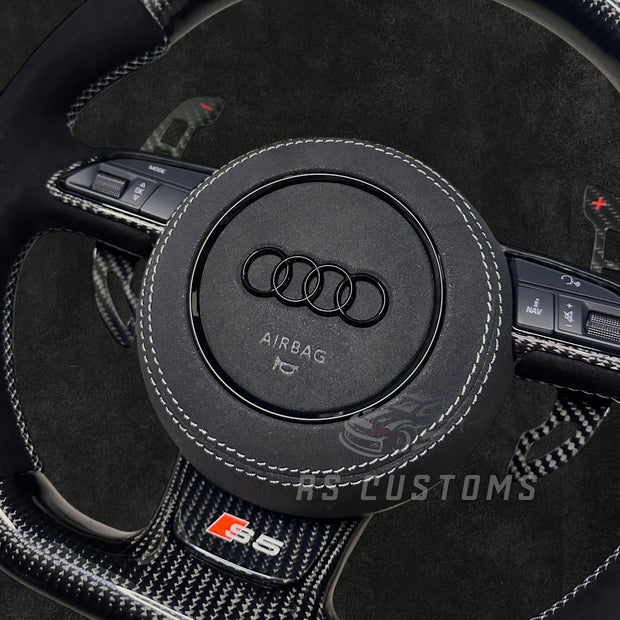 RS CUSTOMS Audi RS steering wheel with carbon fiber, Alcantara, and white stitching. Features a white racing stripe at 12 o'clock.