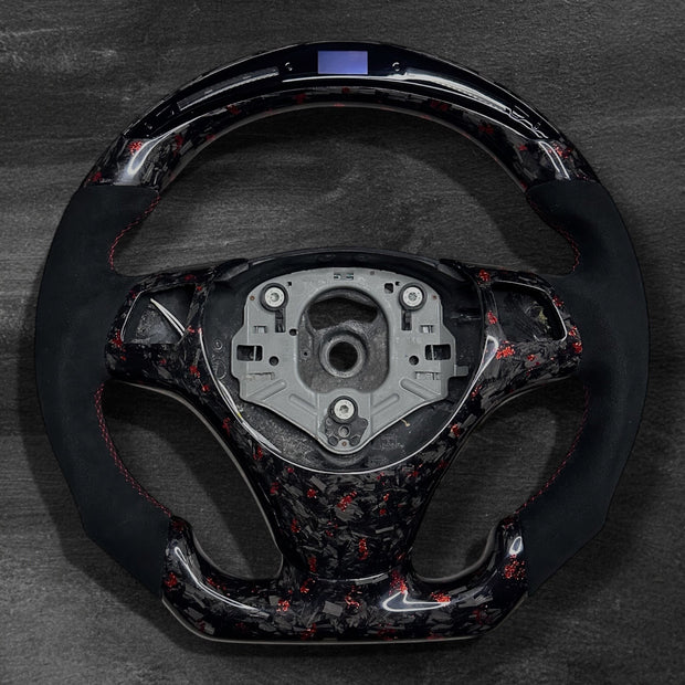 RS Customs BMW E-Series custom steering wheel with forged carbon fiber, customizable colored flakes, Alcantara grips and integrated LED display for E90, E92, E60, E70 and other BMW E-Series models.