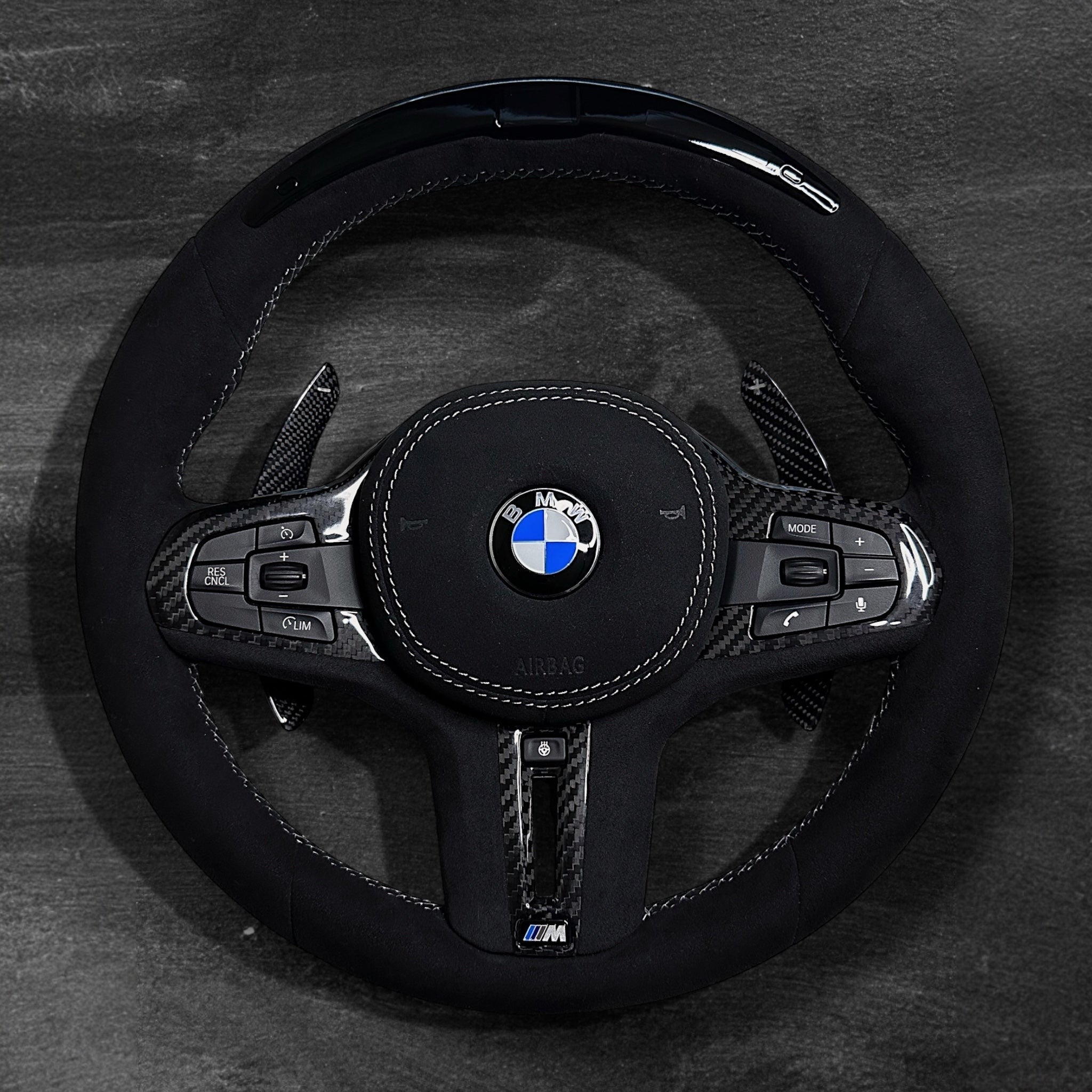 RS Customs BMW G-Series custom steering wheel with full Alcantara finish, carbon fiber details, integrated LED display, optional complete airbag, heating, vibration motor and paddle shifters.