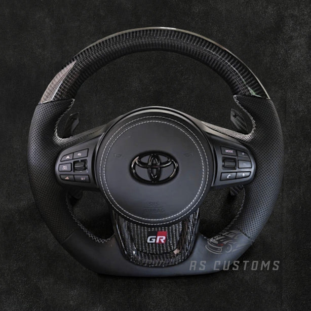 RS Customs Toyota GR Supra MK5 Facelift custom steering wheel for 2023+ A90 and A91 models with customizable leather, Alcantara, carbon fiber, forged carbon and LED display options.