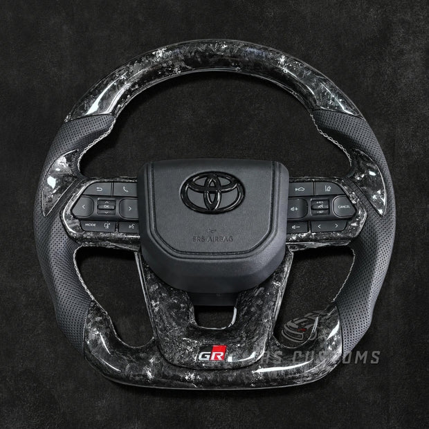 RS Customs Toyota Land Cruiser GR custom steering wheel with forged carbon fiber, colored flakes, perforated leather grips, forged carbon trim and optional custom airbag cover.